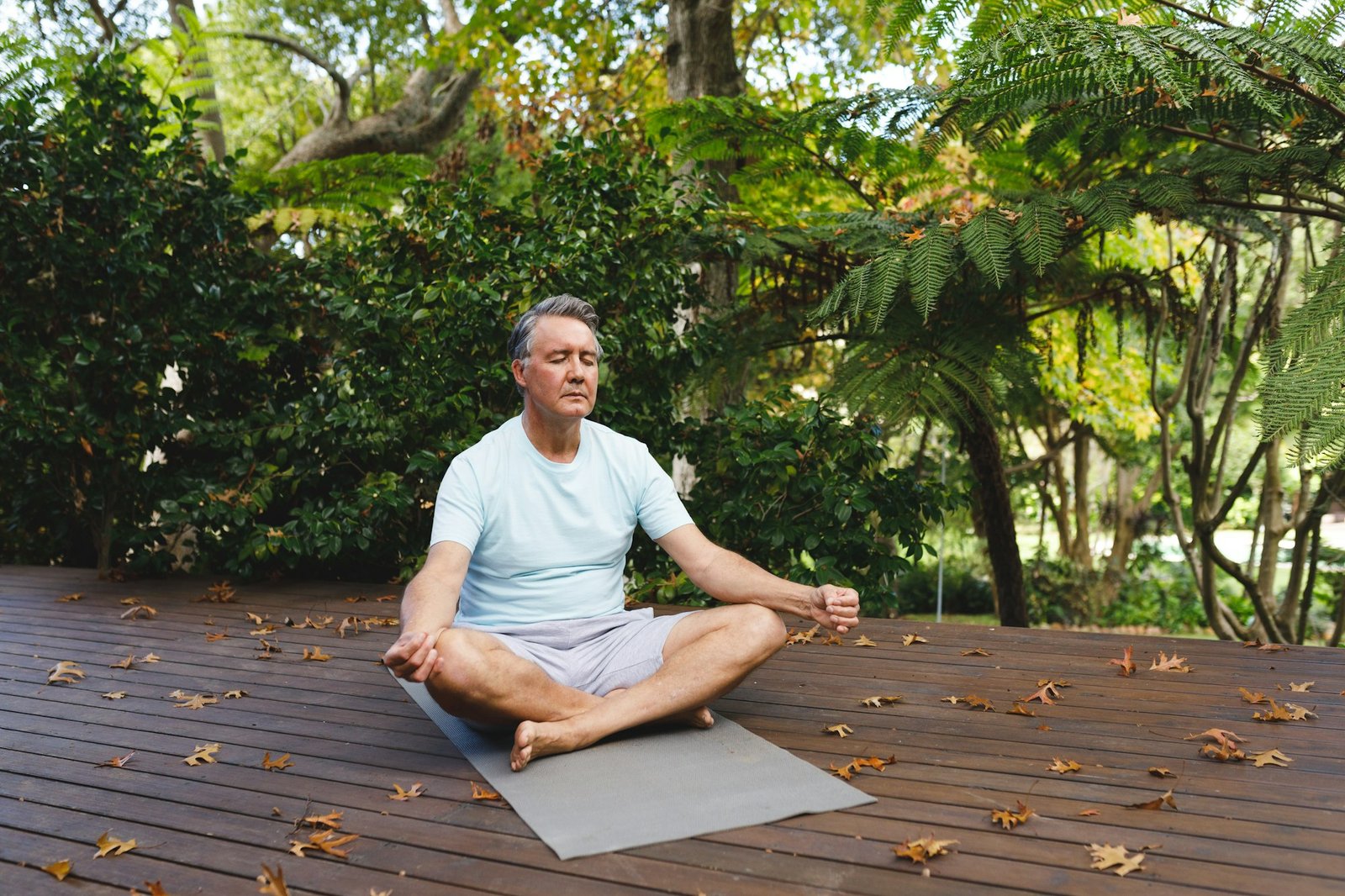 Relaxed senior caucasian man practicing yoga, meditating in garden